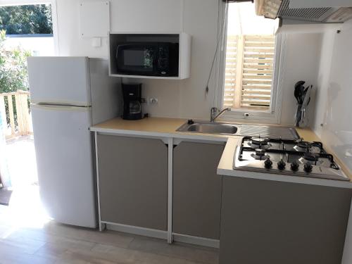 y cocina con fogones, fregadero y nevera. en Mobilhome 6 pers avec Clim, en Saint-Georges-de-Didonne