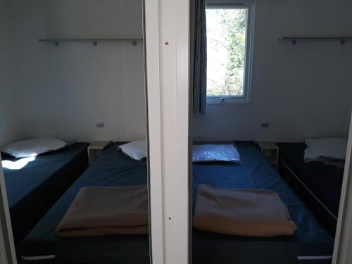 - 2 lits dans une chambre avec fenêtre dans l'établissement Mobilhome 6 pers avec Clim, à Saint-Georges-de-Didonne