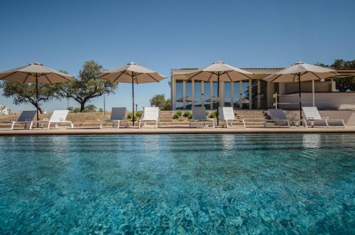 - une piscine avec des chaises longues et des parasols dans l'établissement La Dehesa de Don Pedro, à Monesterio