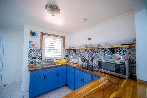 cocina con armarios azules y microondas en Lovely Condo near monkey habitat and beach, en Quepos