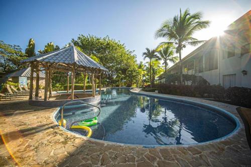a swimming pool with a water slide and a gazebo at Lovely Condo near monkey habitat and beach in Quepos