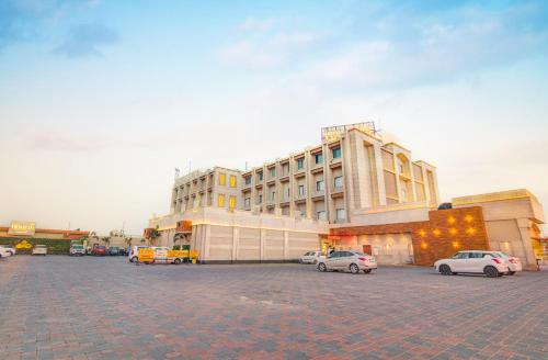 un grande edificio con auto parcheggiate in un parcheggio di Hotel Home In By Amrik Sukhdev a Sonipat