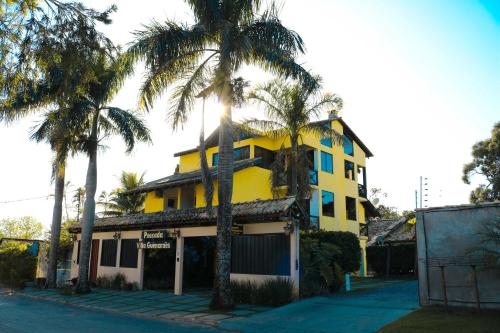 un edificio amarillo con palmeras delante en Pousada Villa Guimaraes, en Chapada dos Guimarães