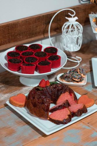 Una mesa con dos platos de pasteles y cupcakes. en Pousada Villa Guimaraes, en Chapada dos Guimarães