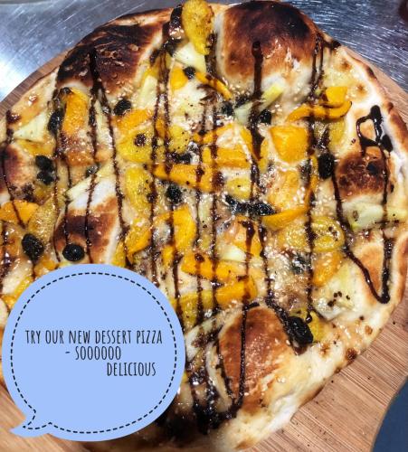 a pizza sitting on a wooden cutting board with a sticker at Camotes-Hidden-Huts in San Francisco