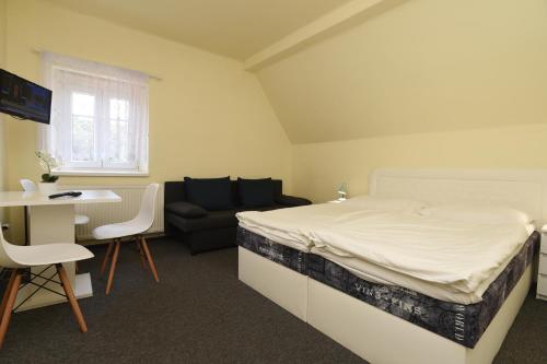 a bedroom with a bed and a couch and a table at Hotel U Jezírka in Liberec