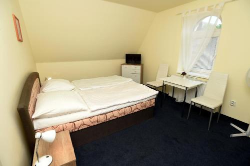 a bedroom with a bed and a table and chairs at Hotel U Jezírka in Liberec