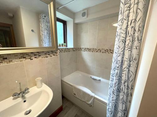 a bathroom with a tub and a sink and a bath tubermottermott at Pass the Keys Beautiful Apartment - Outstanding Central Location in Dumfries