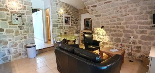 a living room with a leather couch and a stone wall at MAS LE CORBERY in Largentière