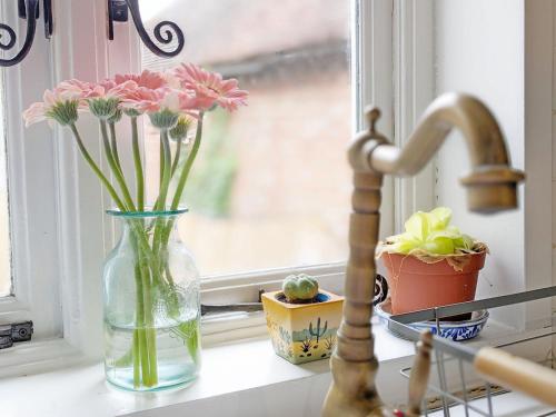 um vaso com flores cor-de-rosa sentado no peitoril da janela em Robins Rest, Billingshurst em Billingshurst