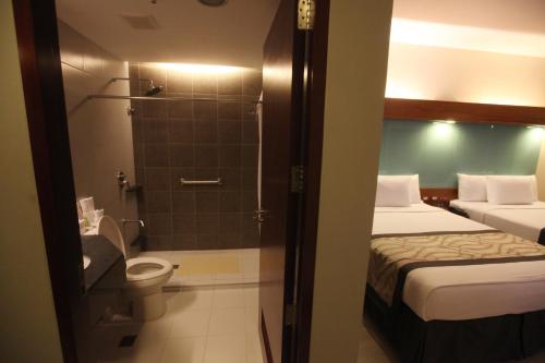 a bathroom with two beds and a shower with a toilet at Microtel by Wyndham UP Technohub in Manila
