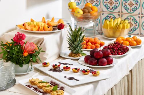 a table filled with plates of fruit and desserts at Hotel Ascot Riccione in Riccione