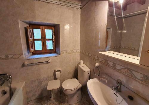 a bathroom with a toilet and a sink and a window at Vivienda Vacacional Casa Casenti in Villanueva de Ardisana
