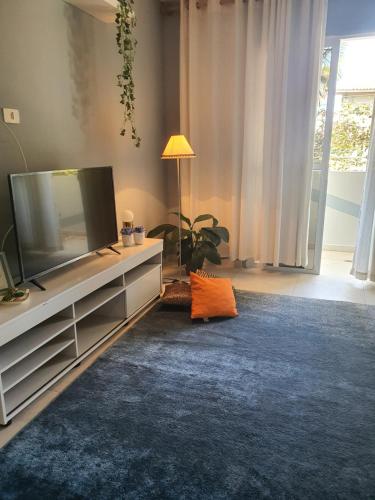 Una sala de estar con un televisor de pantalla plana en un centro de entretenimiento. en Jequiti-Mar Apto aconchegante na Enseada, en Guarujá