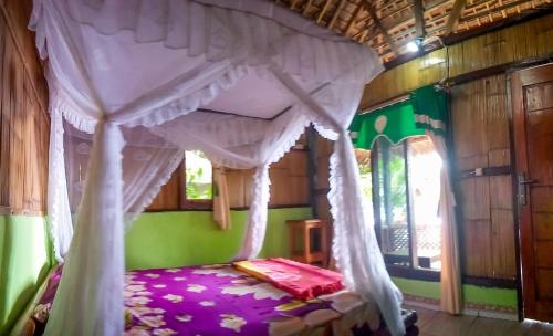 a bed with a canopy in a room at Sunset Cottages in Hitokalak