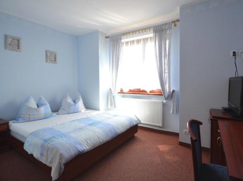 a bedroom with a bed with blue walls and a window at Dworek Morski in Kołobrzeg