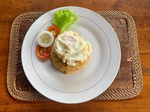 a white plate with an egg and tomatoes on a table at Budi Sun Resort, Flores, Maumere in Maumere