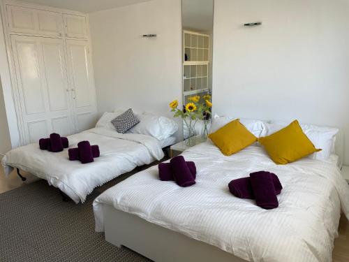 two beds in a room with purple and yellow pillows at Holiday Home Fulham in London