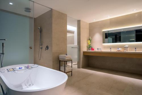 a bathroom with a tub and a shower and a sink at Feathers- A Radha Hotel, Chennai in Chennai