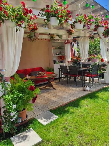 een patio met een tafel, stoelen en bloemen bij Casa Doina in Rîşnov