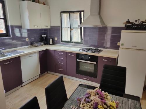 una cocina con armarios morados y una mesa con flores. en Holiday home Barbaroša, en Sveti Filip i Jakov