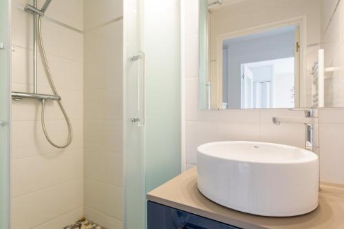 a white bathroom with a sink and a shower at Le Valet in Saint-Cast-le-Guildo