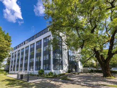 an office building with a tree in front of it at Limehome München in Munich