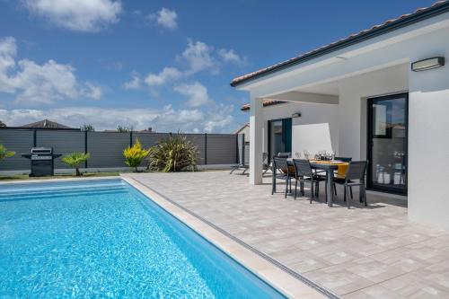 - une piscine avec une table et des chaises à côté d'une maison dans l'établissement Maison moderne avec piscine pour 6, à La Plaine-sur-Mer