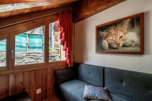 una foto di un gatto sul muro accanto a un divano di Baita dal Gat by Quokka 360 - modern wooden chalet in Faido a Sobrio