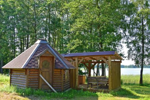 a wooden cabin with a bench and a gazebo at Duriu sodyba in Molėtai