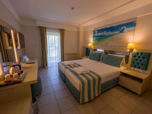 a hotel room with a large bed with a painting on the wall at AQI Hydros Club in Kemer