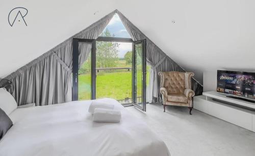 a bedroom with a bed and a chair and a window at Dorney Barn, Close To Windsor Legoland in Dorney
