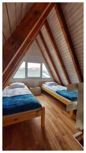 a attic room with two beds and a window at ALOHA Rowy in Rowy