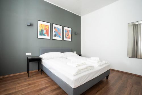 um quarto com uma cama com lençóis brancos e uma mesa em Lovely 2-bedroom apartment next to Praterstern em Viena