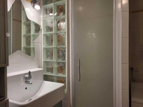 La salle de bains est pourvue d'un lavabo et d'une douche avec une porte en verre. dans l'établissement Charmant 2 pièces, balcon ensoléillé, proche pistes et commerces, séjour et chambre bien équipés - FR-1-449-18, à Tignes