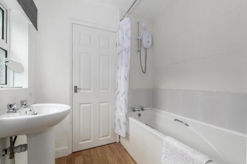a white bathroom with a sink and a bath tub at Spacious & Unique Family and Contractor House & Parking & A1 Road in Grantham