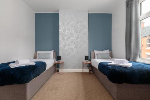 2 łóżka w pokoju z niebieskimi ścianami i oknami w obiekcie Spacious & Unique Family and Contractor House & Parking & A1 Road w mieście Grantham