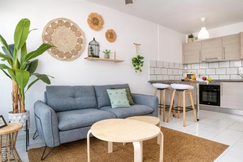 een woonkamer met een blauwe bank en een keuken bij Chez Carmen Allegranza - Pool View - By Lanzarote Vacation Homes in Puerto del Carmen