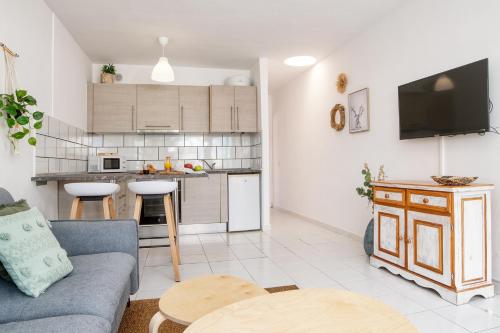 een woonkamer met een bank en een keuken bij Chez Carmen Allegranza - Pool View - By Lanzarote Vacation Homes in Puerto del Carmen