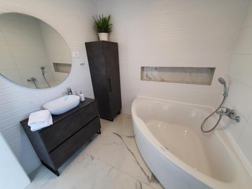 a bathroom with a tub and a sink and a mirror at Little Getaway in Veliki Broćanac