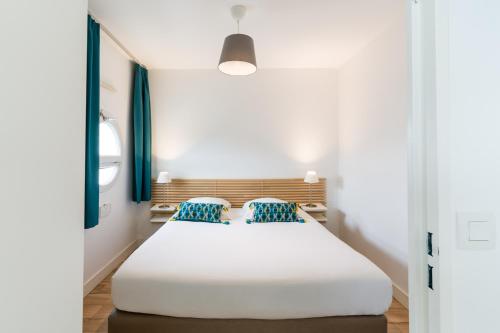 ポーにあるアパート ホテル ビクトリア ガーデン ポーのベッドルーム(青い枕の大きな白いベッド付)