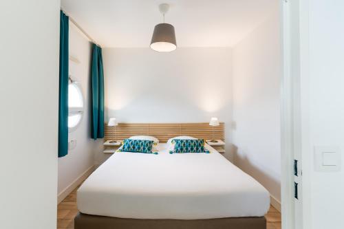 a bedroom with a large white bed with blue pillows at Appart'hotel Victoria Garden Pau in Pau