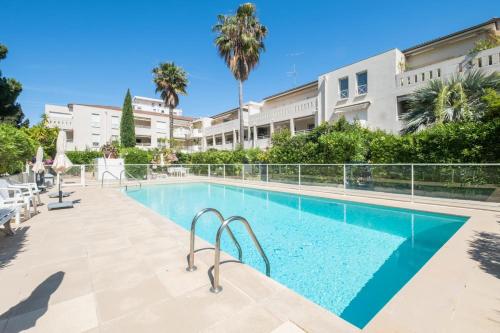 une piscine devant un immeuble avec des palmiers dans l'établissement  Idéal famille  Appartement tout confort dans résidence avec piscine !, à Cannes