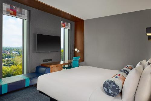 a hotel room with a bed and a tv and window at Aloft London Excel in London