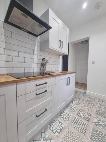 uma cozinha com armários brancos e piso em azulejo em Highly Modern home, 3 bed, close to the Lake District em Barrow in Furness