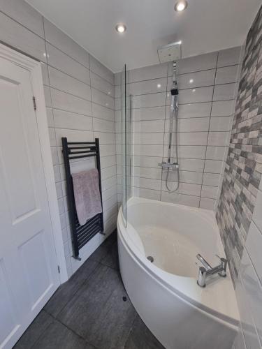 uma casa de banho branca com uma banheira e um chuveiro em Highly Modern home, 3 bed, close to the Lake District em Barrow in Furness