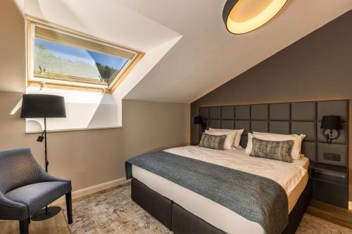 a bedroom with a bed and a window and a chair at MONDI Resort und Chalet Oberstaufen in Oberstaufen