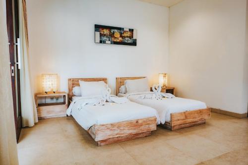 two twin beds in a room with two lamps at Bali Diamond Estates & Villas in Keramas