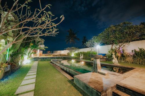 a garden with a pool at night at Bali Diamond Estates & Villas in Keramas