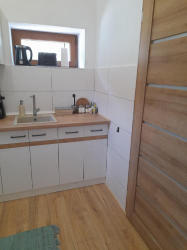 a kitchen with white cabinets and a sink and a door at Kaland apartman II. in Sátoraljaújhely